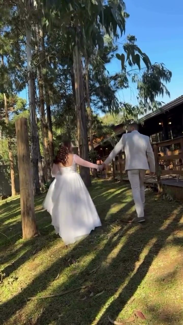 Noivos caminhando de mãos dadas pelo bosque